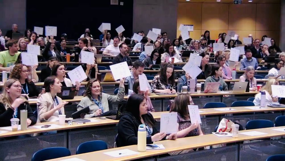An audience holding up whiteboards