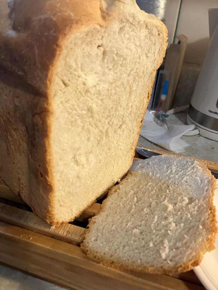 A golden brown crusted, tall loaf of white French style bread with a slice cut from it. 