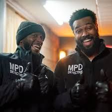 Actors Aldis Hodge and Isaiah Mustafa in the TV adaptation CROSS. They are dressed as cops and both have first-rate beards.