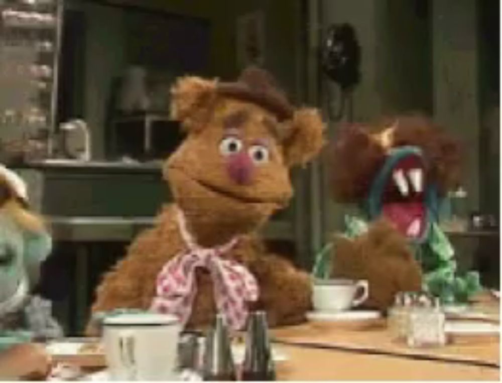 a group of stuffed animals are sitting at a table with cups and saucers