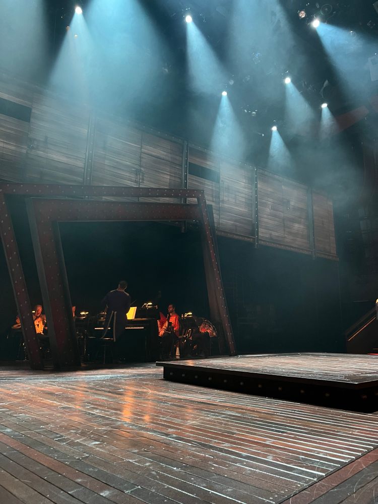 A closer shot of the Wurtele Thrust Stage with dramatic lighting overhead and the band dimly lit in the back.