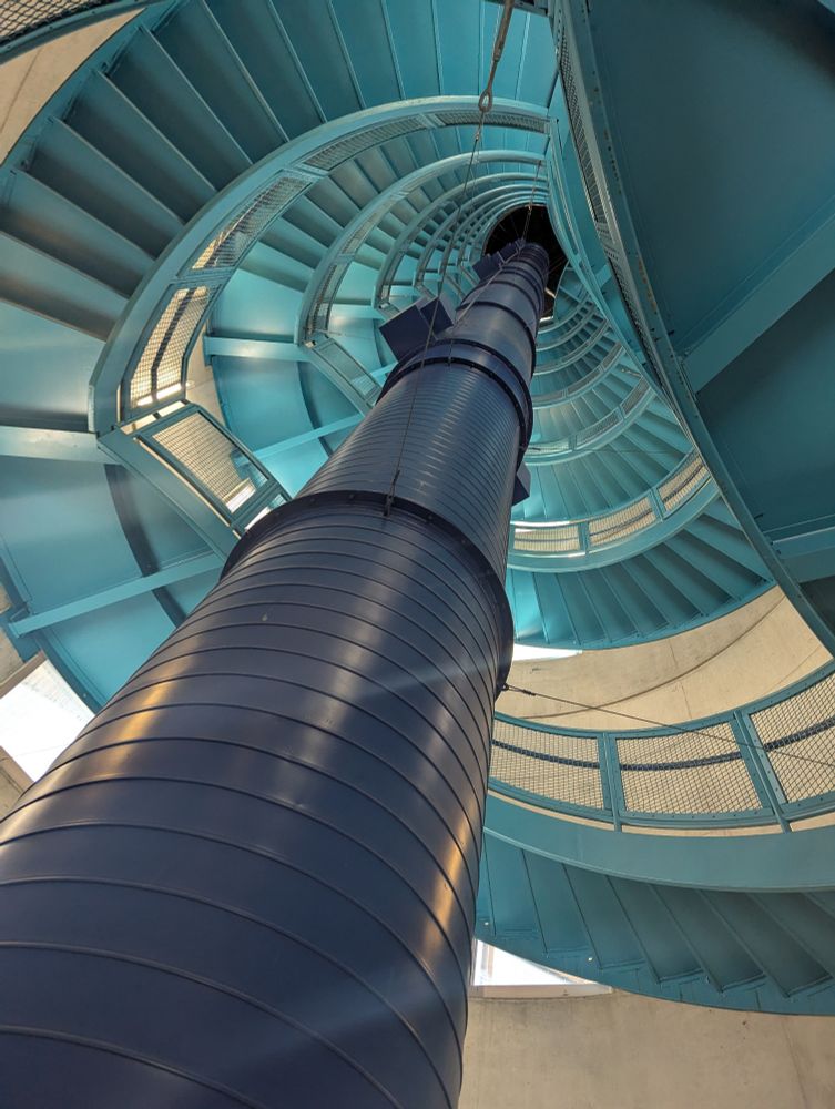 Photo shows an upward view of a very blue industrial looking spiral staircase, inside the Cleveland Public Library.