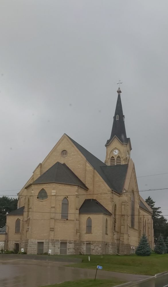 a surprisingly sturdy looking large brick church building with steeple and clock tower