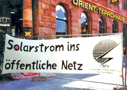 Weißes Banner mit schwarzer Aufschrift „Solarstrom ins öffentliche Netz“ und dem Logo des SFV (Solarenergie-Förderverein Deutschland e. V.) mit stilisierter Sonne und Blitz.