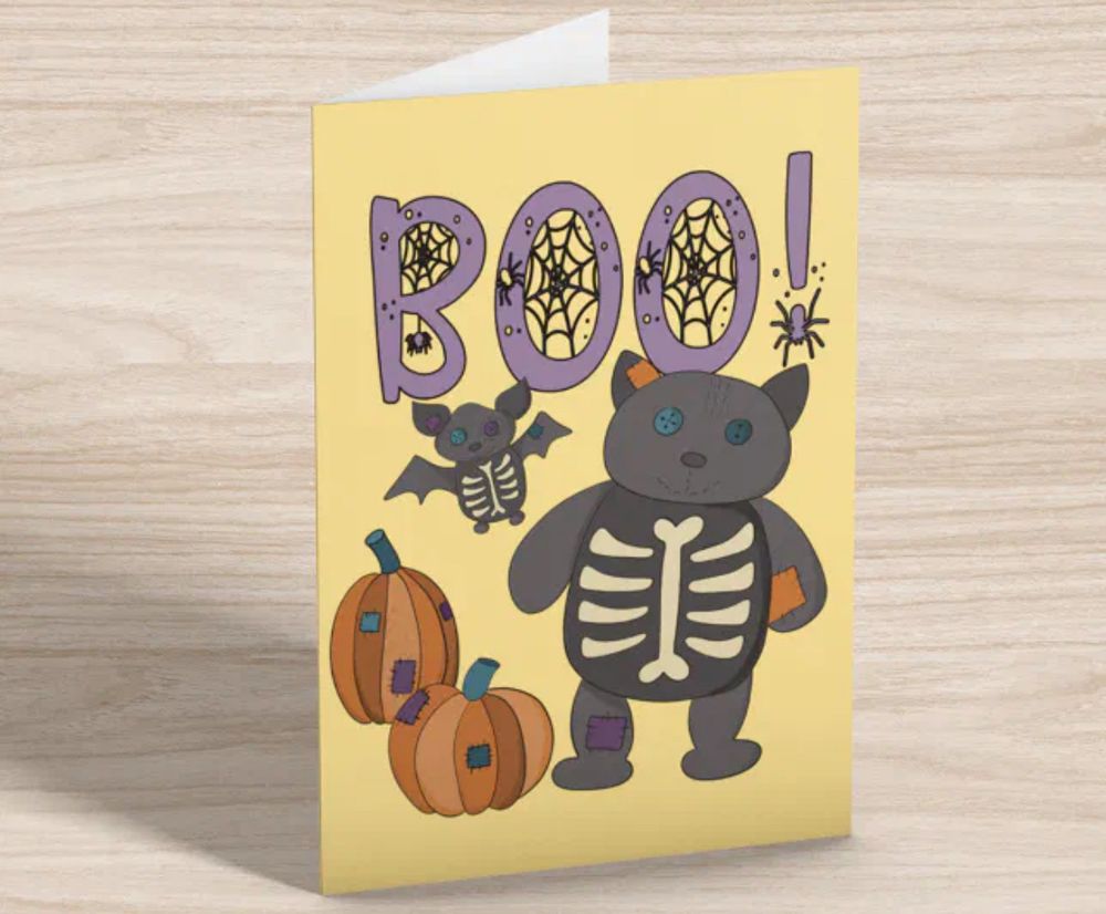 Halloween card with a skeleton cat and bat and patchwork pumpkins along with the word “Boo”