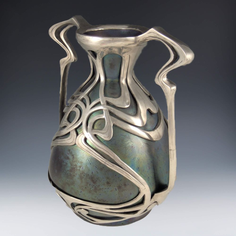 ZSOLNAY ART NOUVEAU PEWTER MOUNTED CERAMIC VASE
ZSOLNAY ART NOUVEAU PEWTER MOUNTED CERAMIC VASE ZSOLNAY ART NOUVEAU PEWTER MOUNTED CERAMIC VASE ZSOLNAY ART NOUVEAU PEWTER MOUNTED CERAMIC VASE
ZSOLNAY ART NOUVEAU PEWTER MOUNTED CERAMIC VASE
Sold / Reserved
Ceramic Art Nouveau vase with polished pewter mount
Manufacturer	Zsolnay
Country of Manufacture	Hungarian
Date	c.1900
Marks	Unmarked
Condition	Perfect
Size	18.5cms high, 16.5cms wide
Reference	Metalwork is possibly by Osiris or Orion