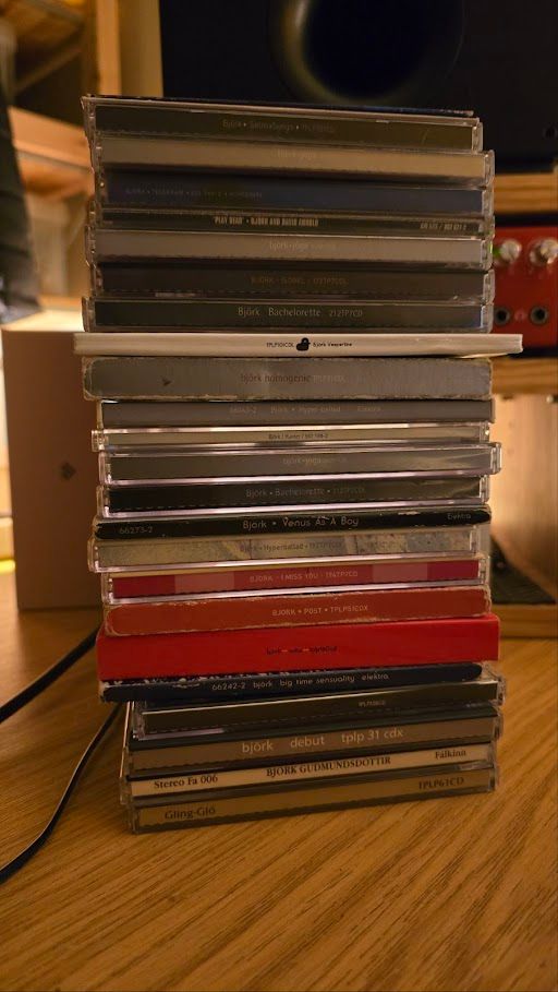 A tower of my Björk CDs sitting on a desk, there are 26 in total. Three you can't see because they're on the top and in thin cardboard sleeves.
