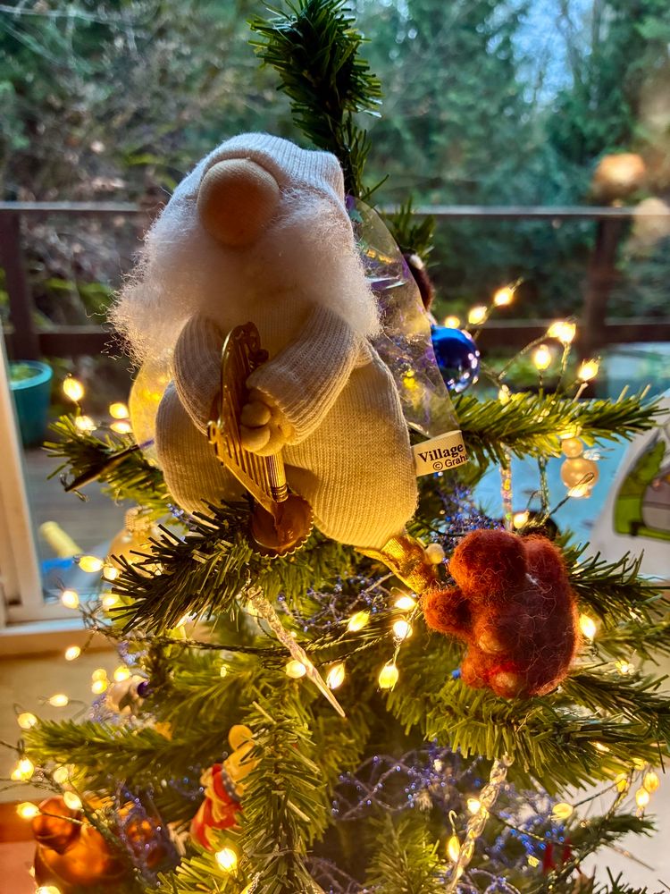 Little bearded angel tree topper in long johns and stocking cap playing a harp. Hand felted squirrel listening next to him.