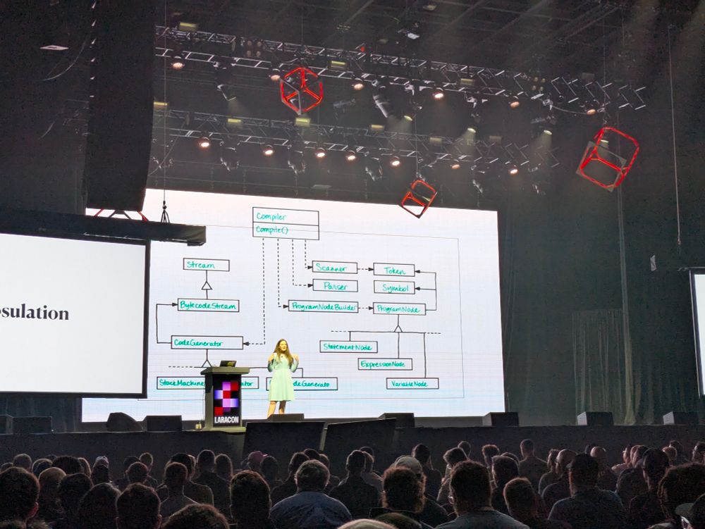 Mary Perry presenting on design patterns at Laracon US 2025. She's standing on stage in front of a screen in front of a large audience 