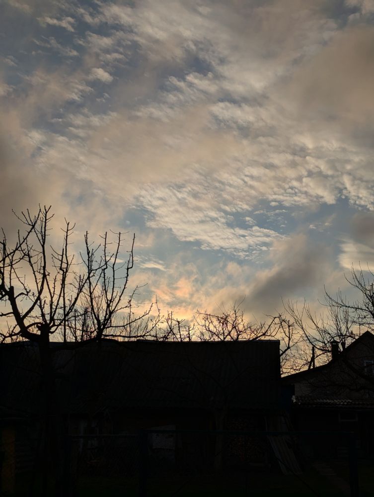 Сонца хаваецца ў аблоках, але добра відаць, што яно там ёсць. Неба фантастычных цёплых пастэльных адценняў.