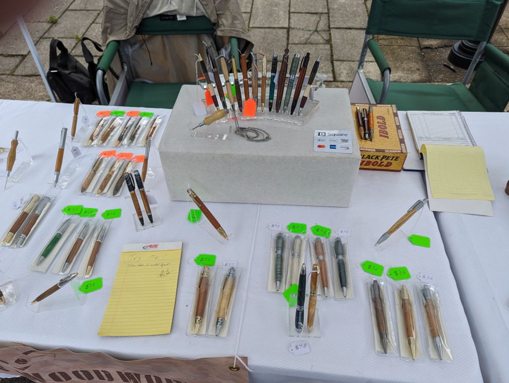 An assortment of wooden pens on a white table.