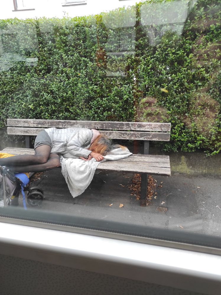 eine obdachlose Frau schläft auf einer Bank