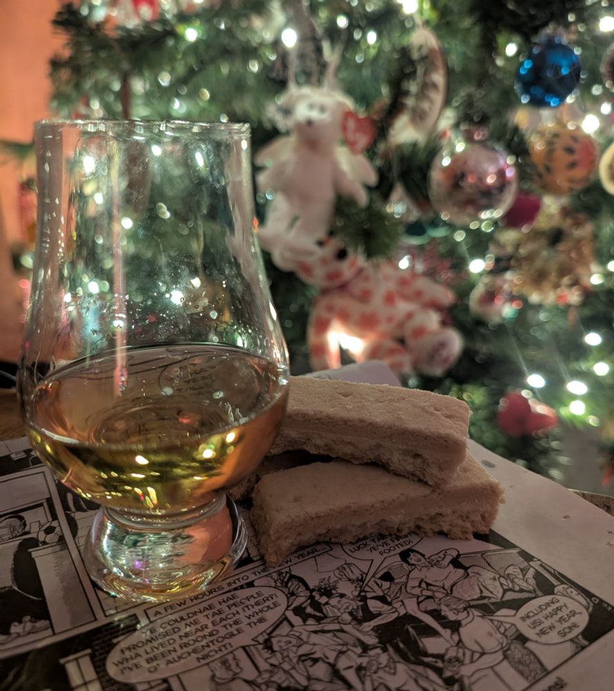 A glass of Glengoyne whisky, shortbread fingers and the Hogmanay edition of The Broons, with Christmas tree lights in the background 