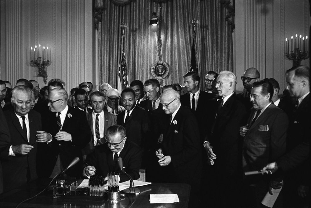 President Lyndon B. Johnson signs the Voting Rights Act on August 6, 1965, as members of Congress and Martin Luther King, Jr. look on.