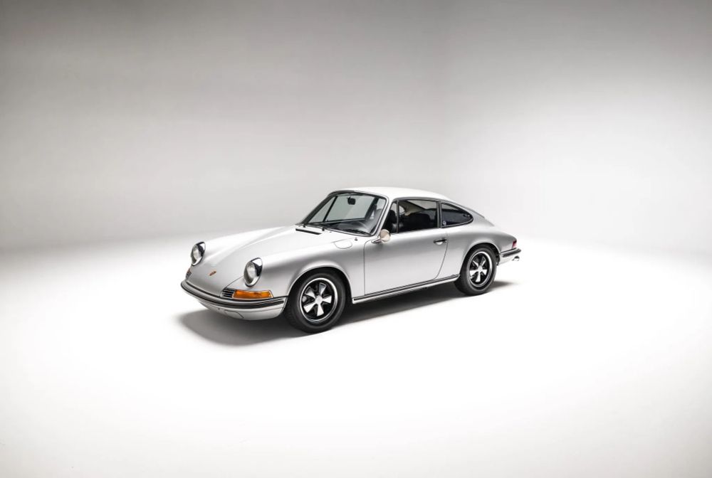 A 1969 Porsche 911E finished in Silver Metallic parked in a studio setting.