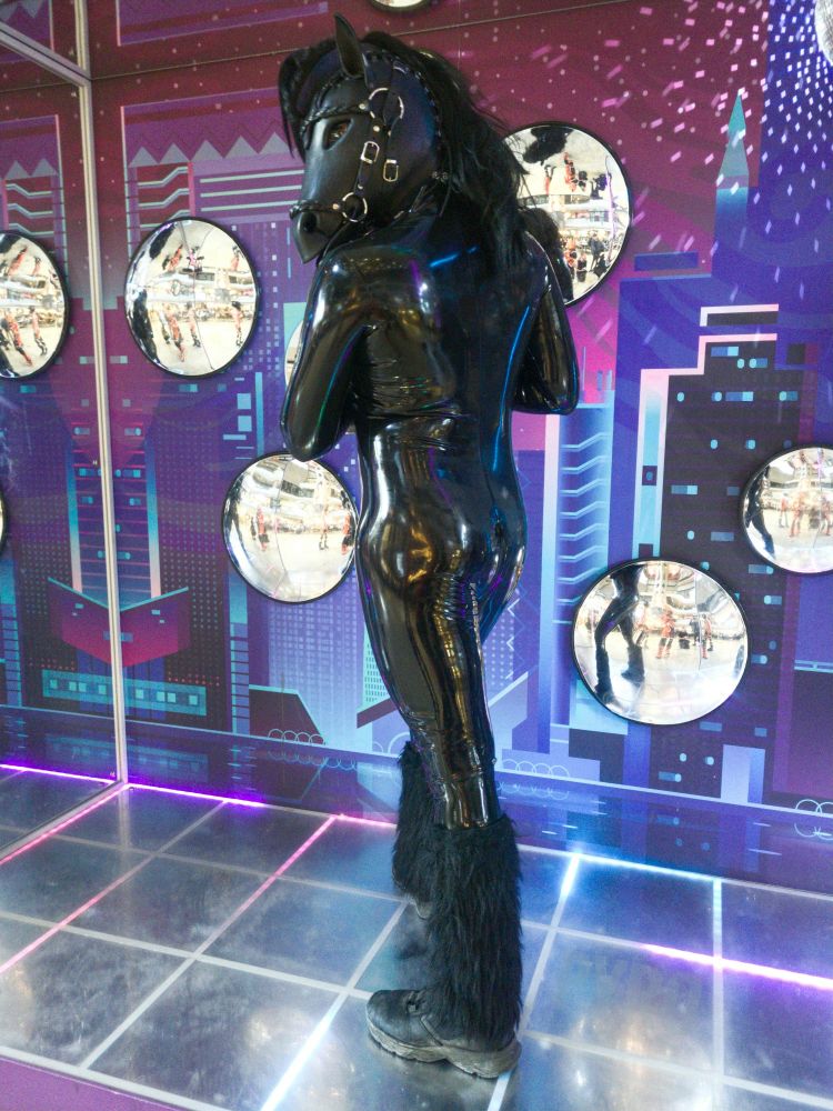 A rubber pony presenting his butt needing help polishing his latex