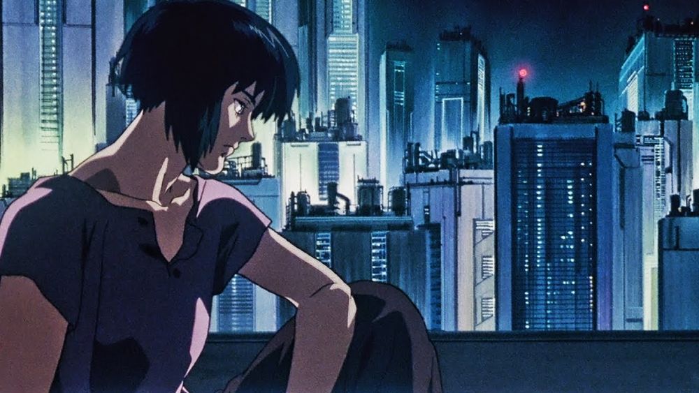 A screenshot from the movie Ghost in the Shell (1995). The Major looks contemplative against the city skyline at night.