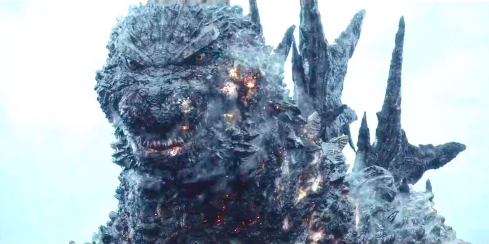Godzilla baring his teeth with burning wounds. He looks a little goofy. 