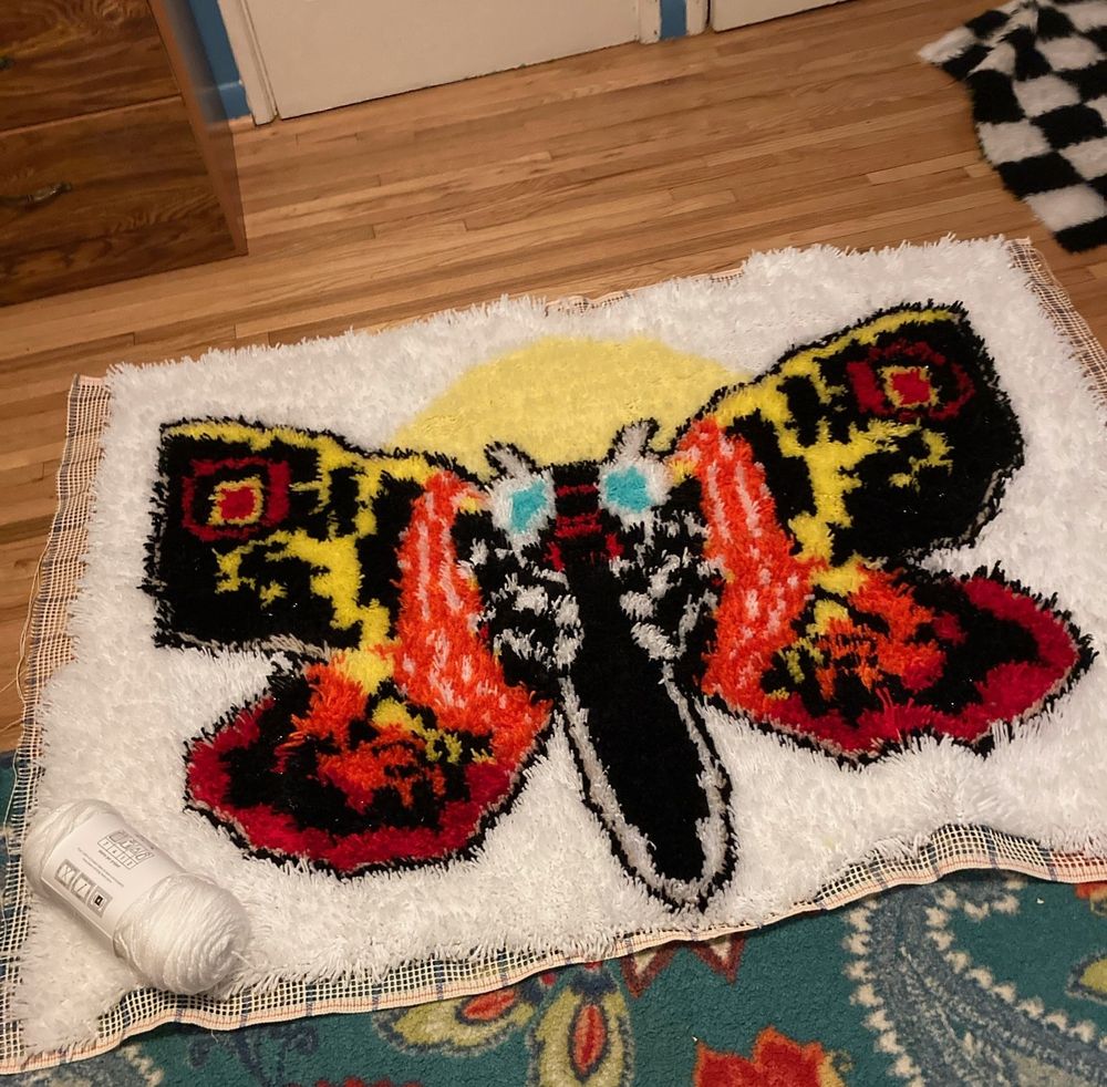 A photograph of Jasmine's Mothra latchhook rug.