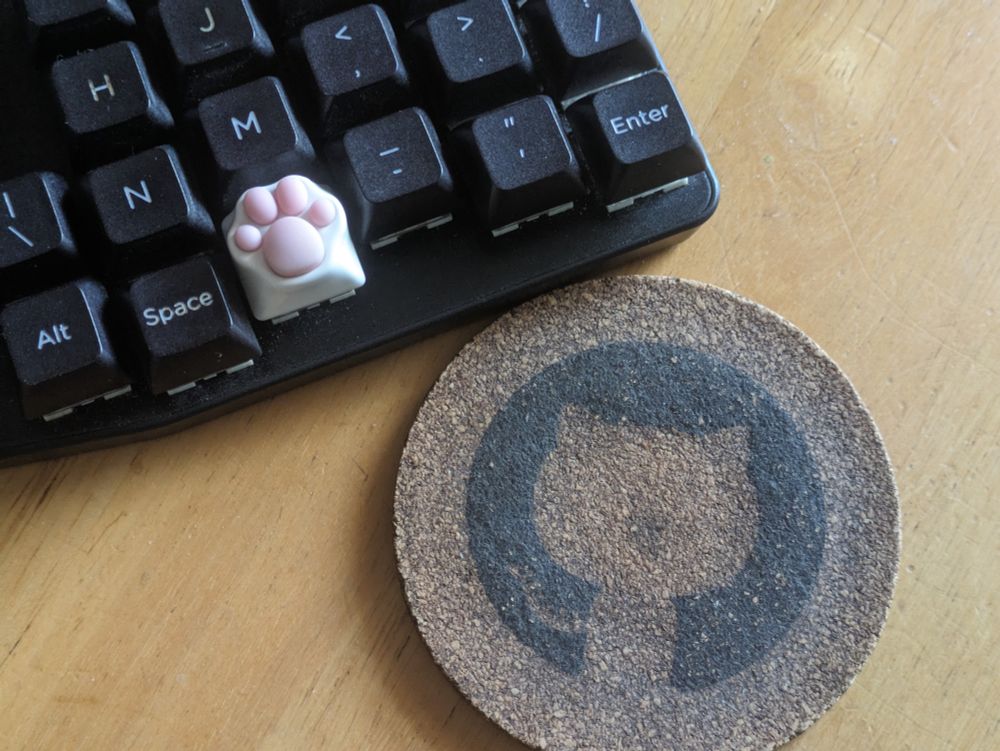 A cat paw keycap and a GitHub coffee coaster