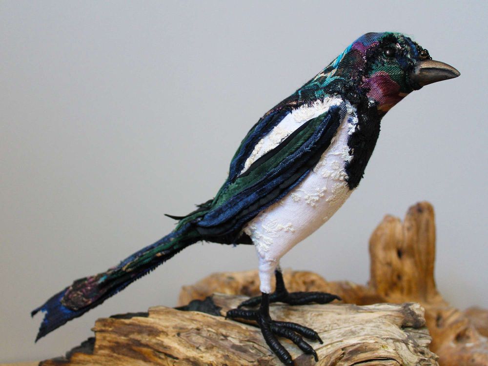 Kleine Elster aus Stoffresten auf einem Holzstück