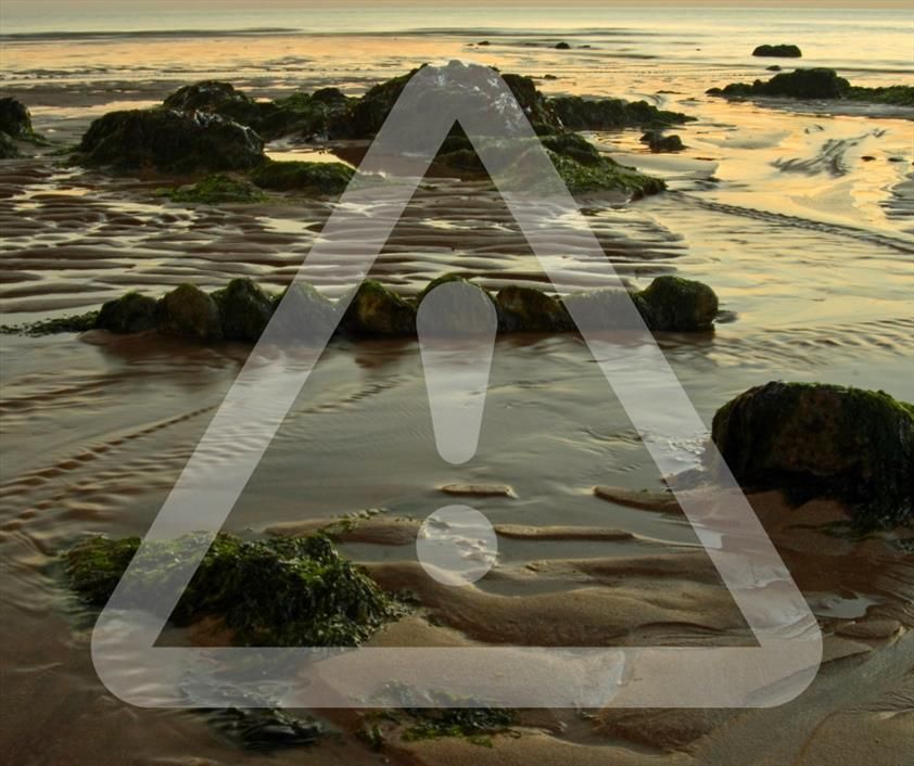 Image shows the ocean with a warning sign over it.