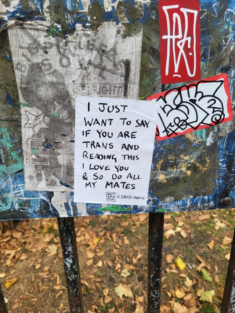 a sign reading "I just want to say if you are trans and reading this I love you & so do all my mates"