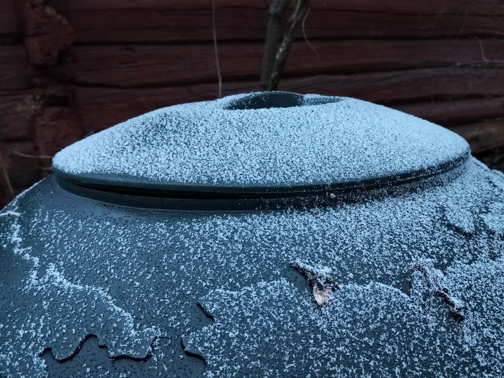 Hento valkoinen lumi/kuurakerros maapallokompostorin päällä. 