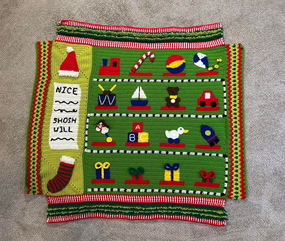 WIP crochet blanket, follow a 6 week crochet along pattern, so 5/6 done. Main image is like a train with each cart having a toy: train, candy cane, ball, kite, car, teddy bear, boat, drum, horse, blocks, duck, rocket, four presents. There’s also a nice list with a Santa hat and stocking, and colorful red white and green border patterns. 🧶 clearly many details and a full border are missing, waiting for week 6. 