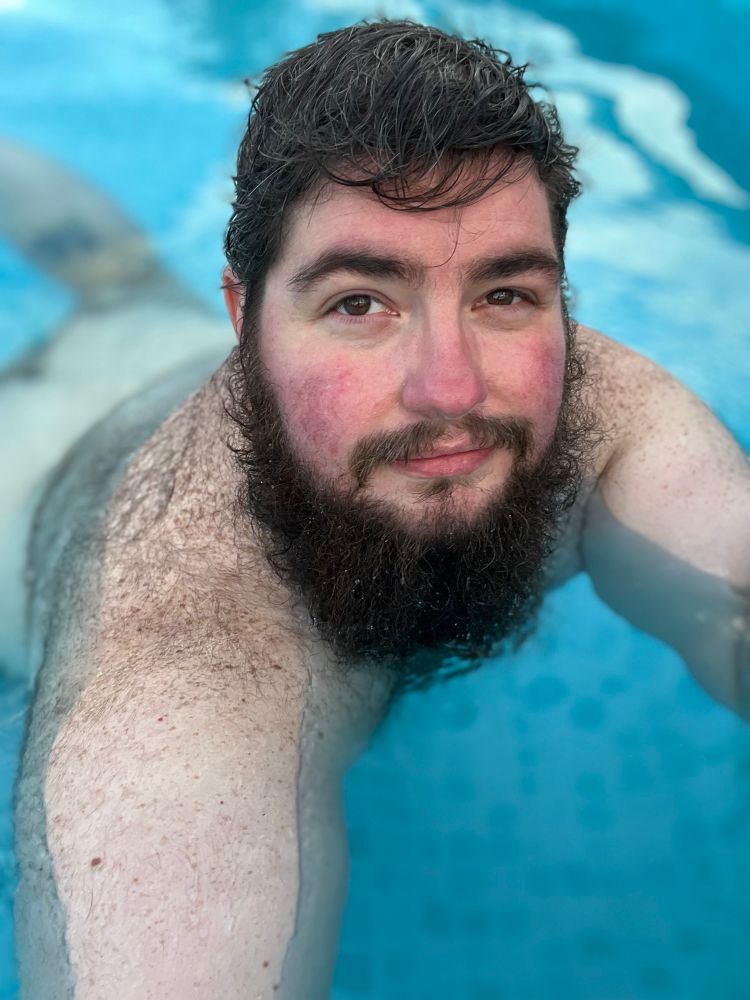 A hairy bearded being chunky dunking (swimming naked)