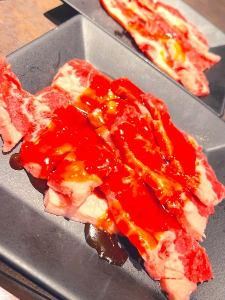 合成樹脂でできた黒い四角のお皿に、上カルビタレ、上カルビ塩の生肉がのっている。
タレは醤油ベースてニンニクと香辛料が少し混ざる。焼き上がりは適量の油分と柔らかさで食べやすい。