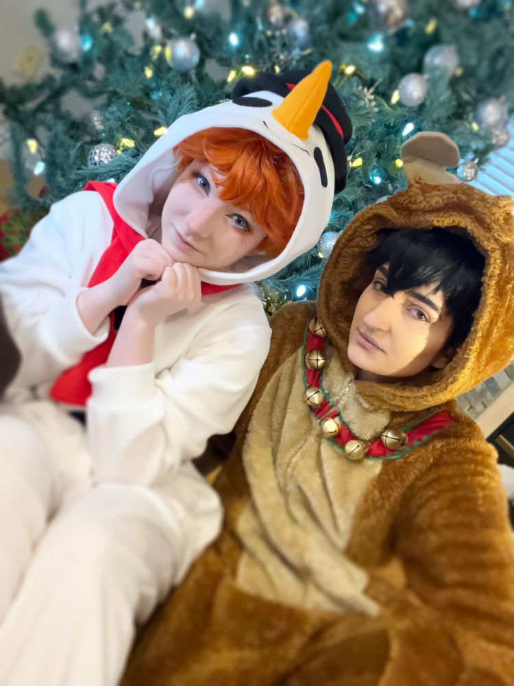 Tobio Kageyama and Shoyo Hinata, Haikyuu, in snowman and reindeer onesies. They are infront of a Christmas tree for the holidays. This is cosplay.