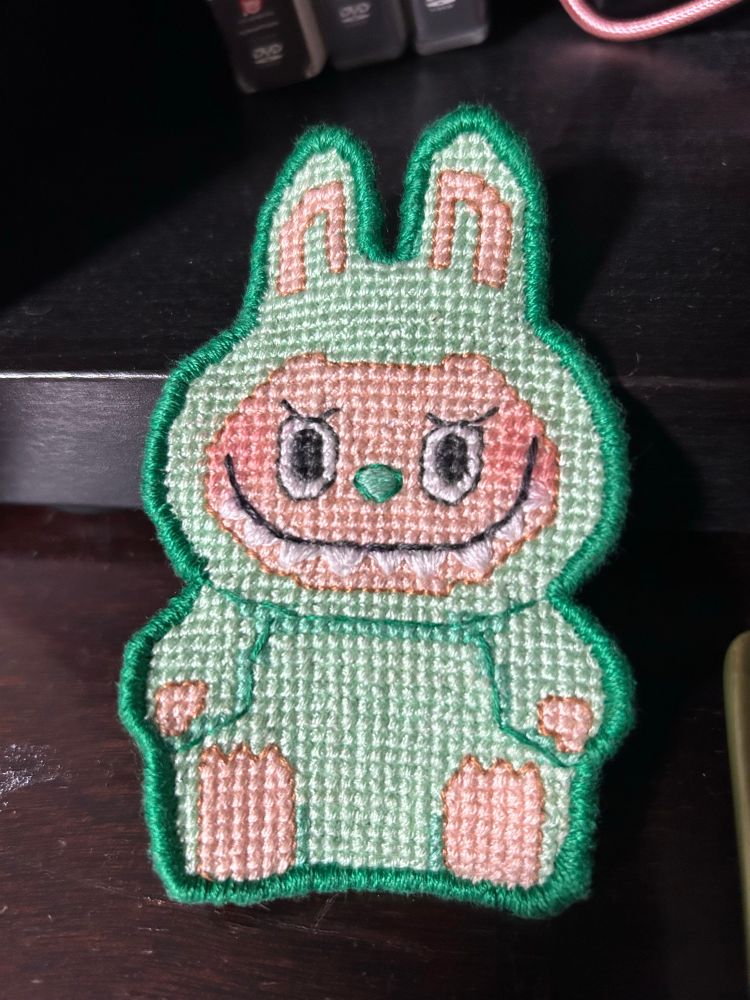 A green stitched patch of a labubu 