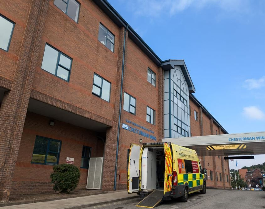 An ambulance parked outside the Chesterman building on a blue sky day.