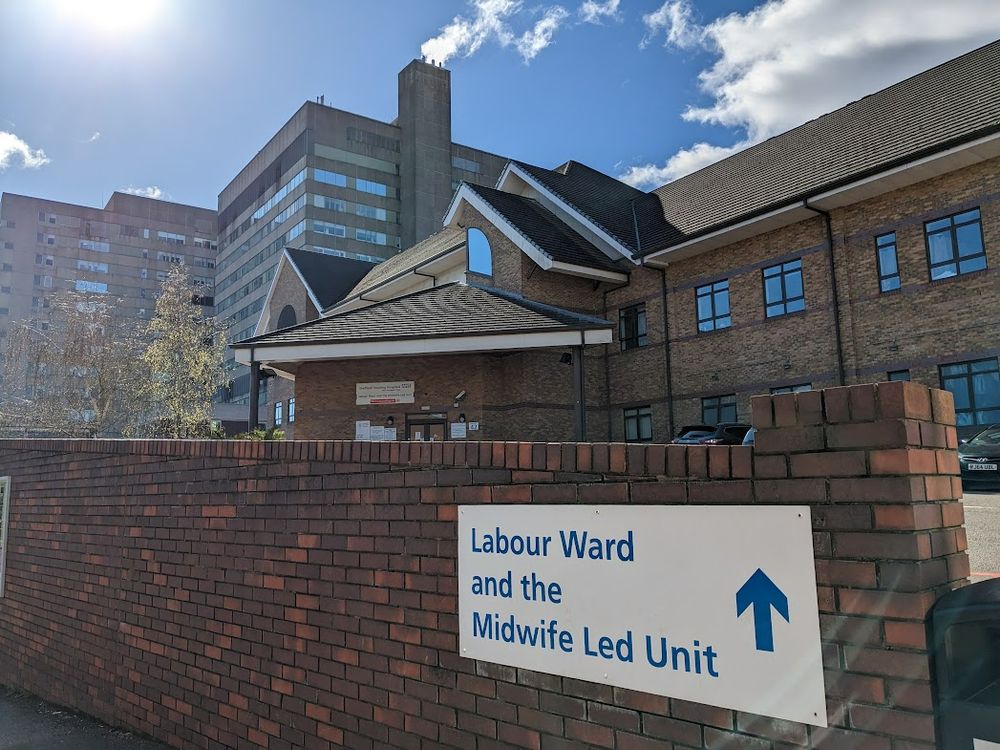 The Royal Hallamshire Hospital building is seen in the background behind the Jessop Wing Maternity Hospital building. In the foreground is signage for the Labour Ward and the Midwife Led Unit.