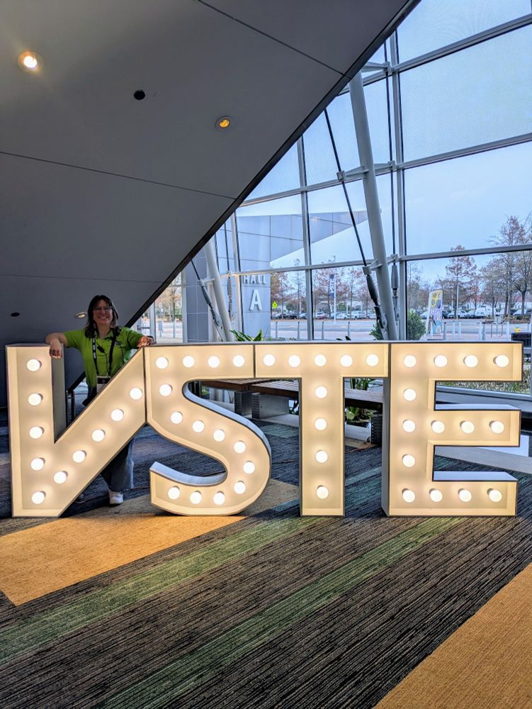 Woman standing behind lit up letters VSTE 