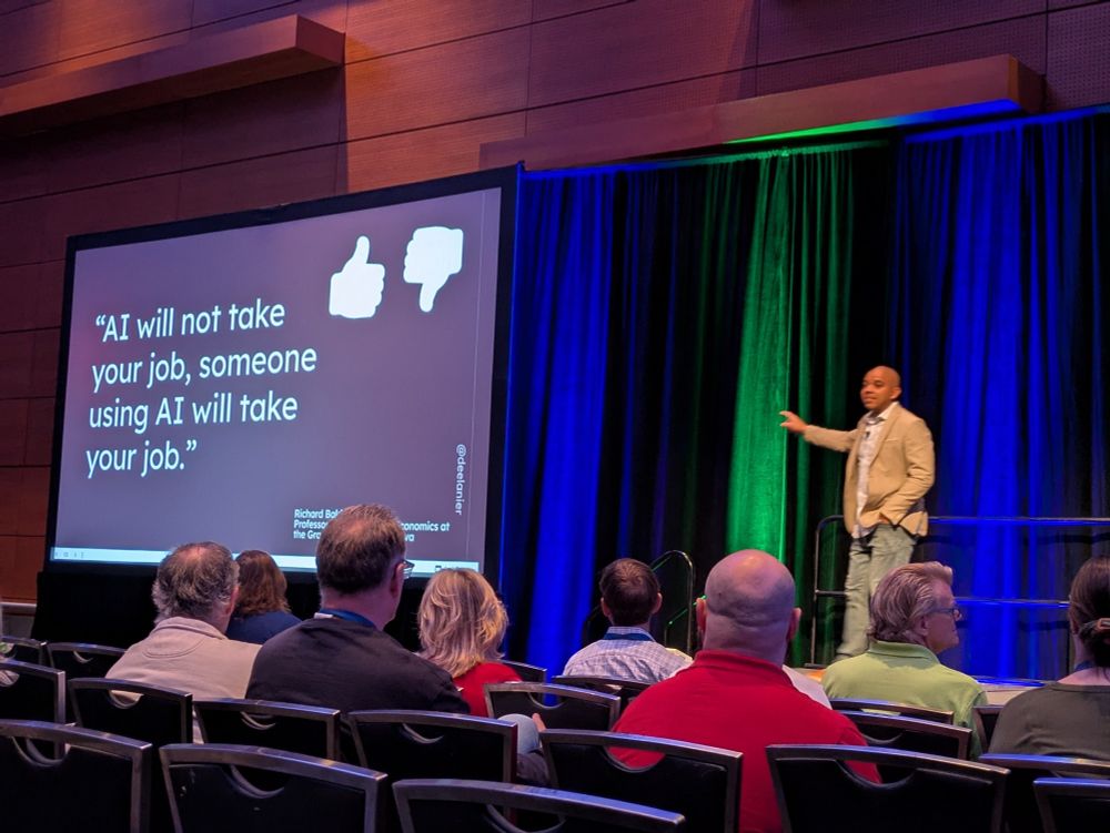 Dee Lanier gesturing to a screen that reads "AI will not take your job, someone using AI will take your job."
