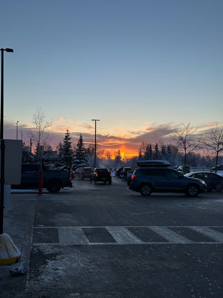 A blaze of orange at the horizon across the Costco parking lot
