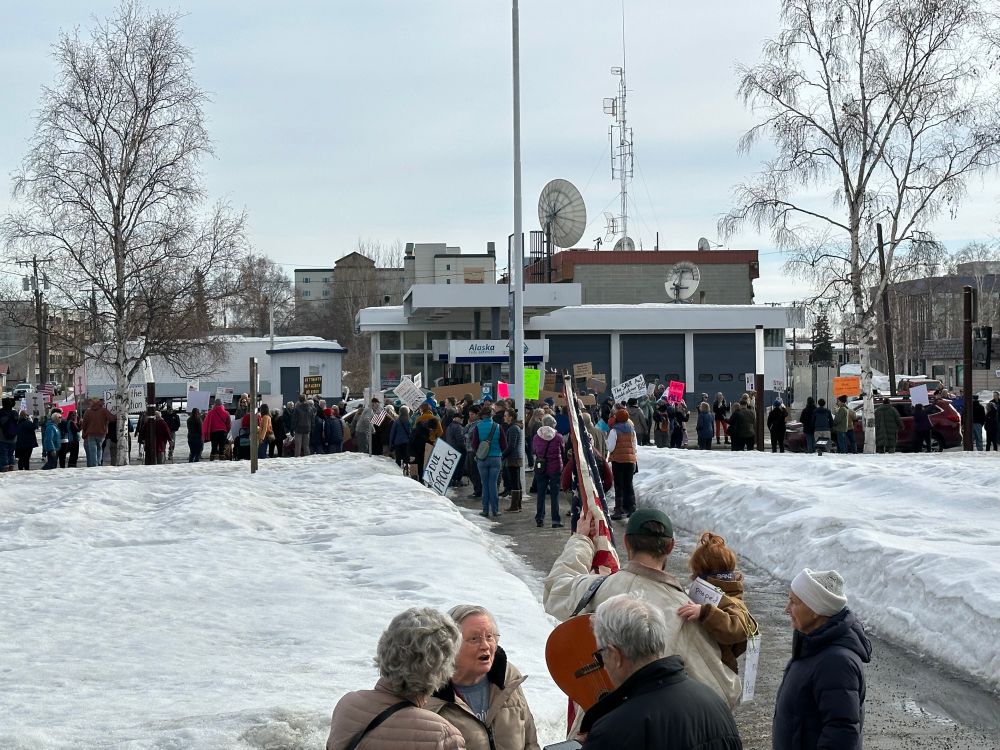 Lots of people lining a road with signs. 