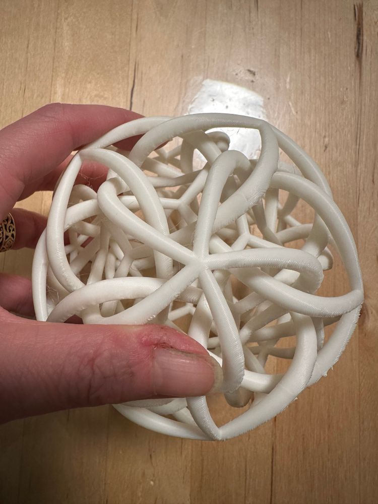 A white twisty entangled icosahedral sculpture, centered on a center of 5-fold rotation