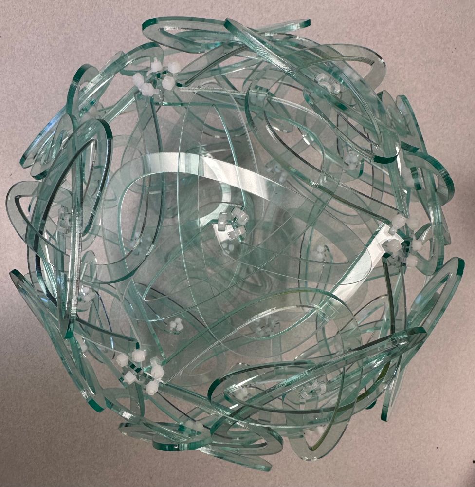 A mathematical sculpture made of 60 interwoven swirly pieces of green glass acrylic, held together with white plastic zip ties