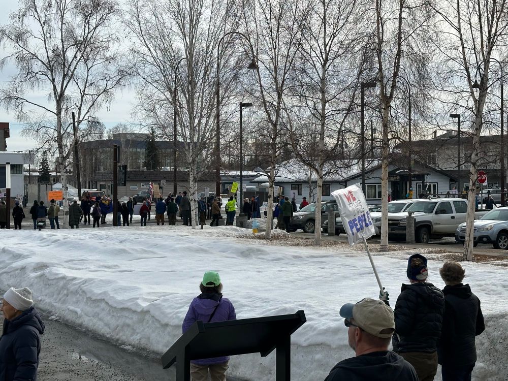 Lots of people lining a road with signs 