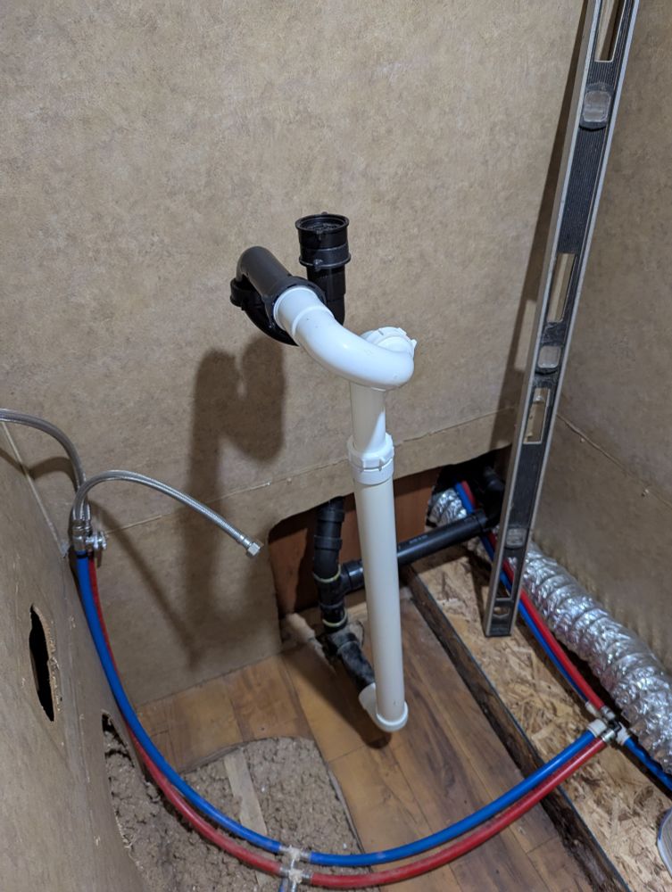A monstrosity of PVC pipe and sink traps sticking out of the wall
