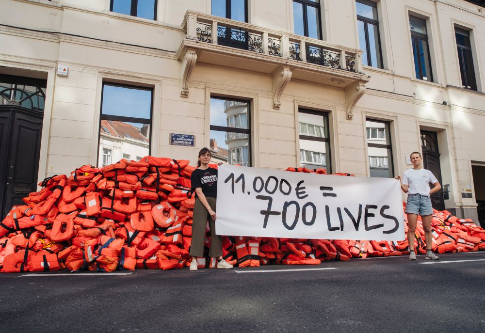 700 Westen vor dem Frontex Büro in Brüssel. Davor unser Advocacy Team mit dem Banner: 11.000€ = 700 Lives
