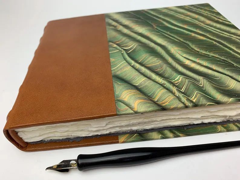 A journal with deckled edges next to a dip pen.