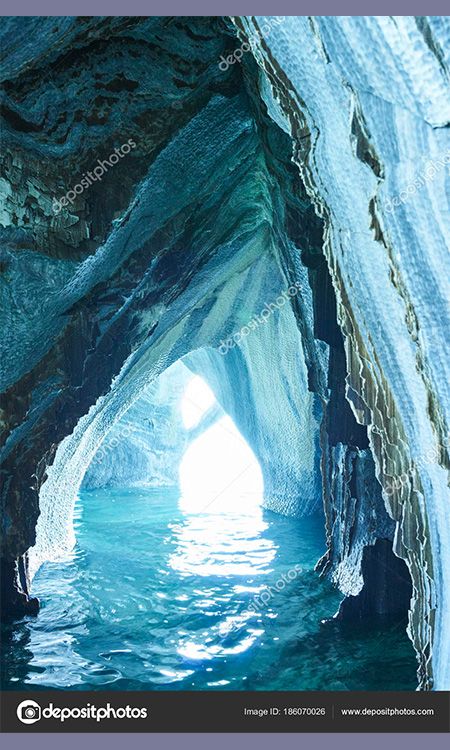 A photo of a marble sea cave full of textures, reflections, and moving water. It is very blue.