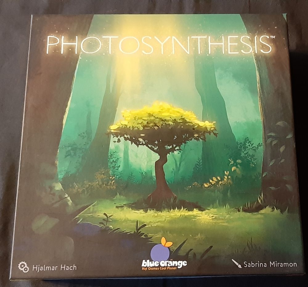 La boîte du jeu Photosynthesis sur laquelle on voit un petit arbre qui capte la lumière du soleil, en dépit des nombreux gros troncs autour