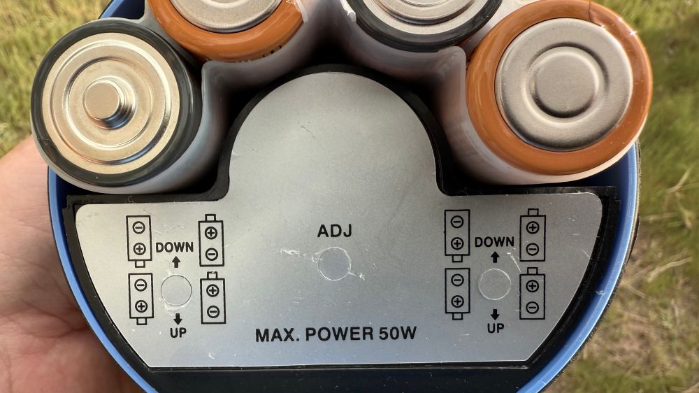 the battery compartment of a pyle megaphone showing how the batteries should be inserted. down is labeled up and up is labeled down. 