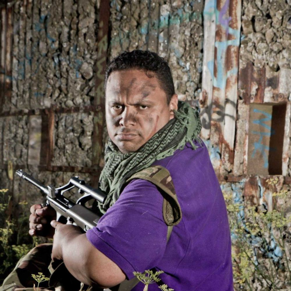 Big Mark dressed in purple, acting out a scene from a war movie