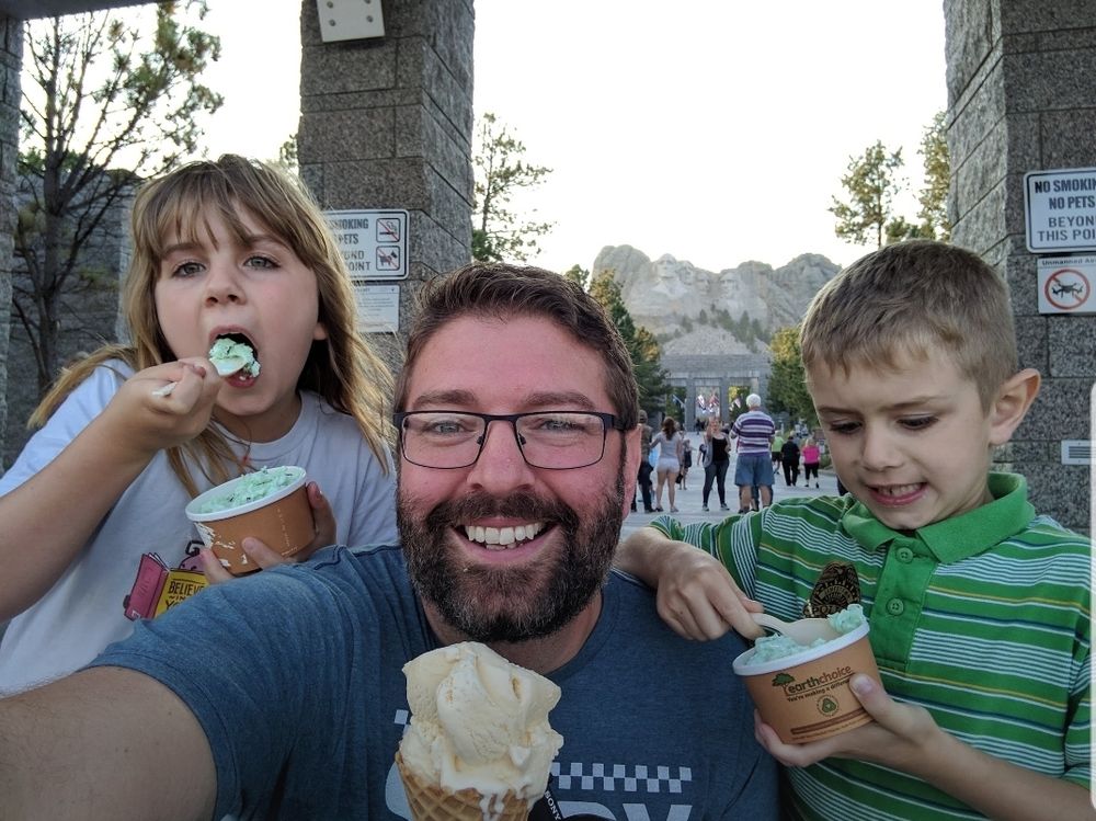A father and his two children enjoying ice cream at Mount Rushmore.